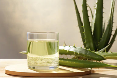 bicchiere con succo di aloe vera e foglie di aloe vera
